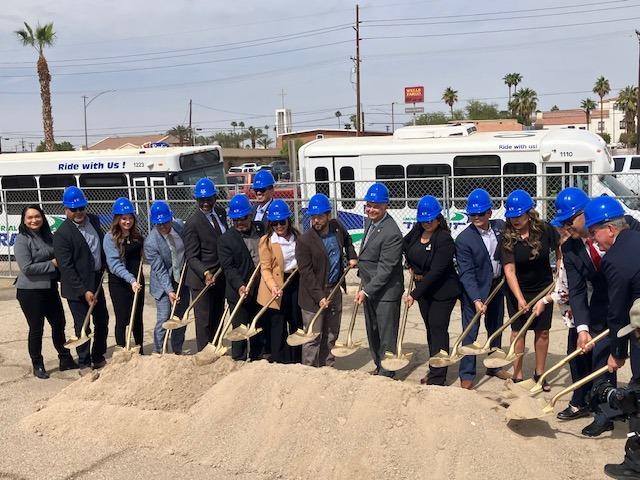 A group of groundbreaking attendees hold shovels to break ground at the site.