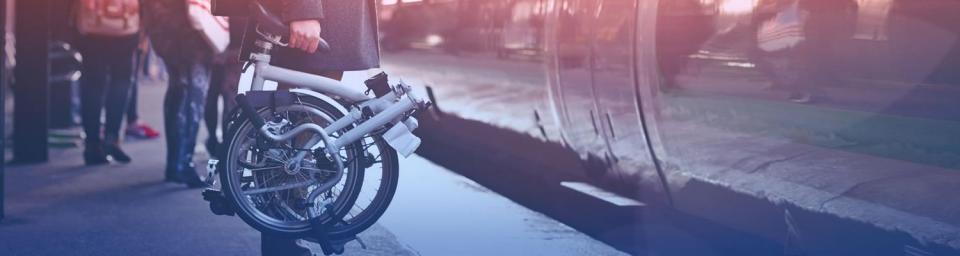 Person holding a collapsible bike waiting for the train