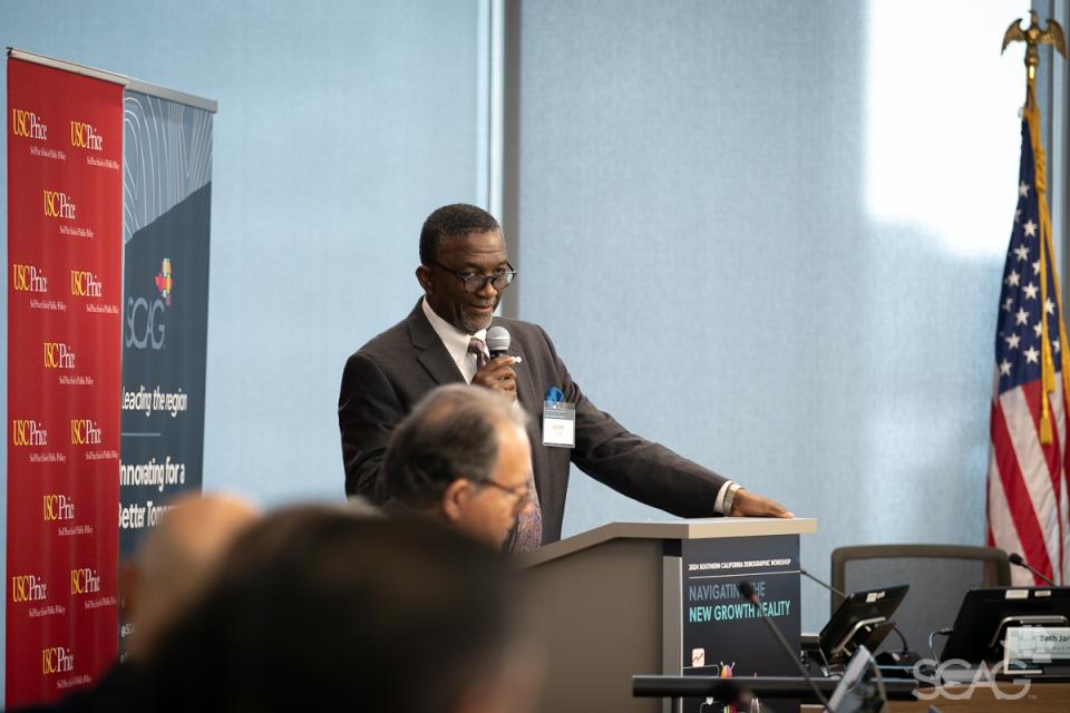 SCAG Executive Director Kome Ajise stands at a podium to  address the attendees at the 2024 Southern California Demographic Workshop.